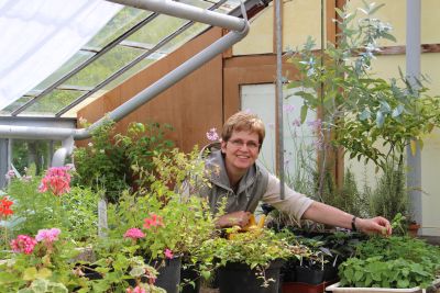 Dr. Andrea Finck steht im Gewächshaus zwischen Kräutern und Geranien. Dr. Andrea Finck steht im Gewächshaus zwischen Kräutern und Geranien.