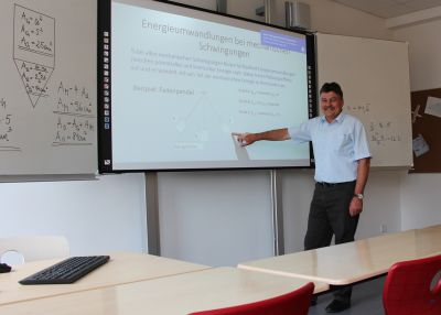 Schulleiter Frank Keck steht in einem Klassenzimmer vor einer grossen weissen Tafel. Foto: Ministerium der Finanzen des Landes Sachsen-Anhalt
