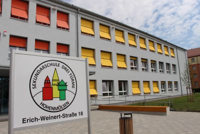 Aussenansicht der Sekundarschule Hohenmölsen. Das Gebäude ist hellgrau geputzt und vor den Fenstern sind gelbe und orangefarbene Sonnenrollos angebracht. Foto: Ministerium der Finanzen des Landes Sachsen-Anhalt