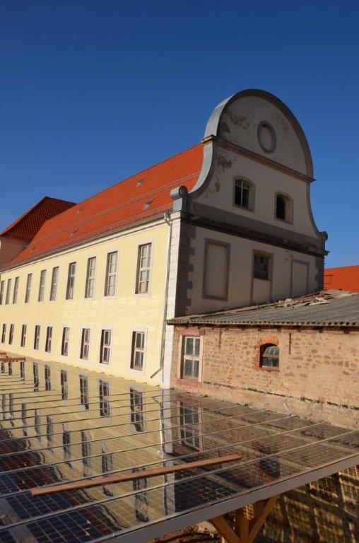 Das Bild zeigt die mit ELER-Mitteln restaurierte Fassade des Gutshauses, die sich in den Solarmodulen spiegelt. Das Bild zeigt die mit ELER-Mitteln restaurierte Fassade des Gutshauses, die sich in den Solarmodulen spiegelt.