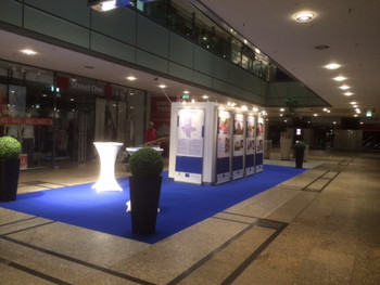 Das Foto zeigt die Wanderausstellung '20 Projekte EFRE/ESF'. Sie steht in der unteren Ladenstraße des Allee Centers Magdeburg auf einem großen, blauen Teppich. Foto: Allee Center