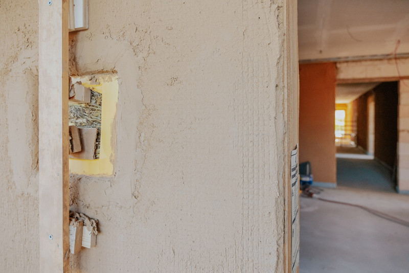Das Bild zeigt eine Wand des Gästehauses, an der noch die Strohballen sichtbar sind, die in den Wänden verbaut sind.
