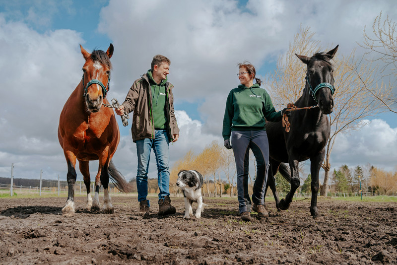 Das Bild zeigt Verena Elschner-Richter und ihren Mann mit zwei Pferden und ihrem Hund.