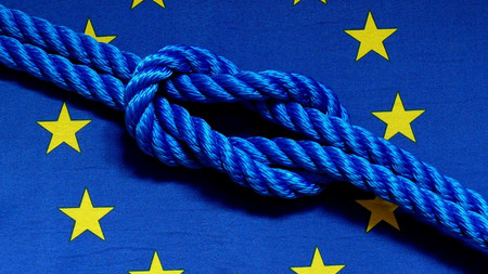 Das Bild zeigt die EU-Flagge mit einem Knoten darin. 