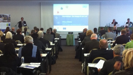 Das Bild zeigt Staatssekretär Dr. Geue im gefüllten Saal bei der Eröffnung des 2. Workshops am 29.10.2012 in Halle/Saale. Foto: IB